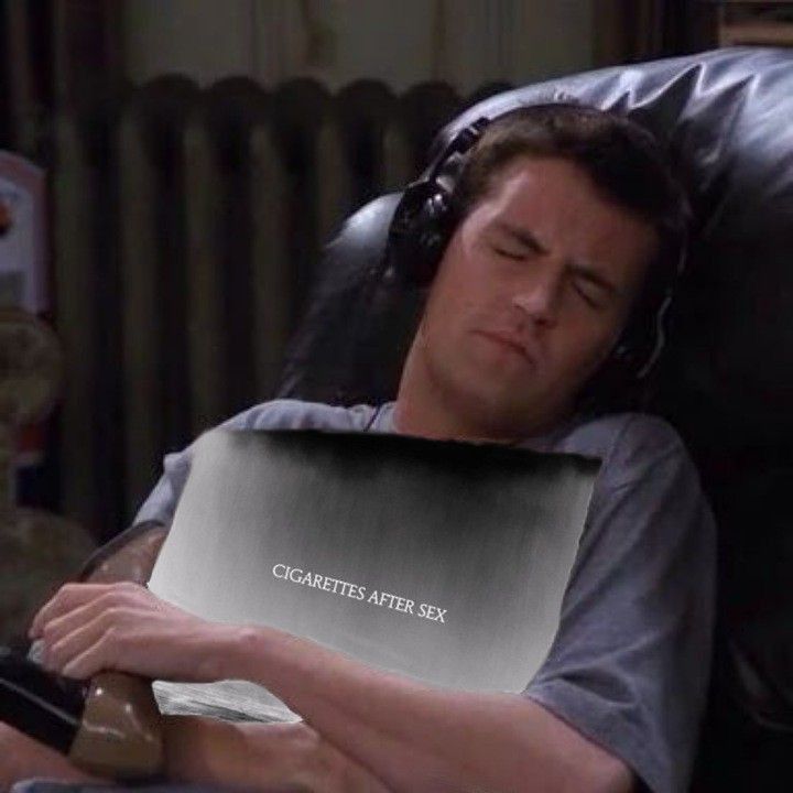 a man laying in a recliner with headphones on his ears and reading a book