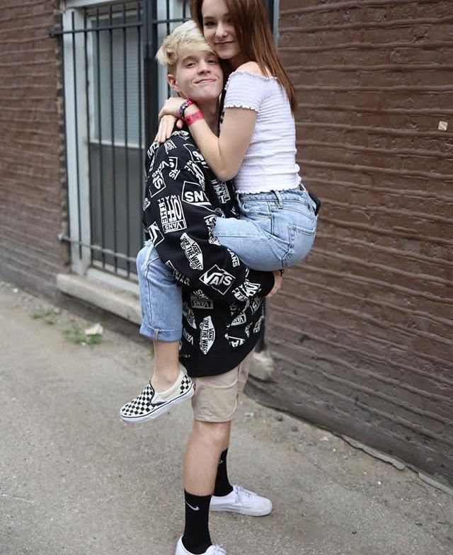 two girls hugging each other in front of a brick building