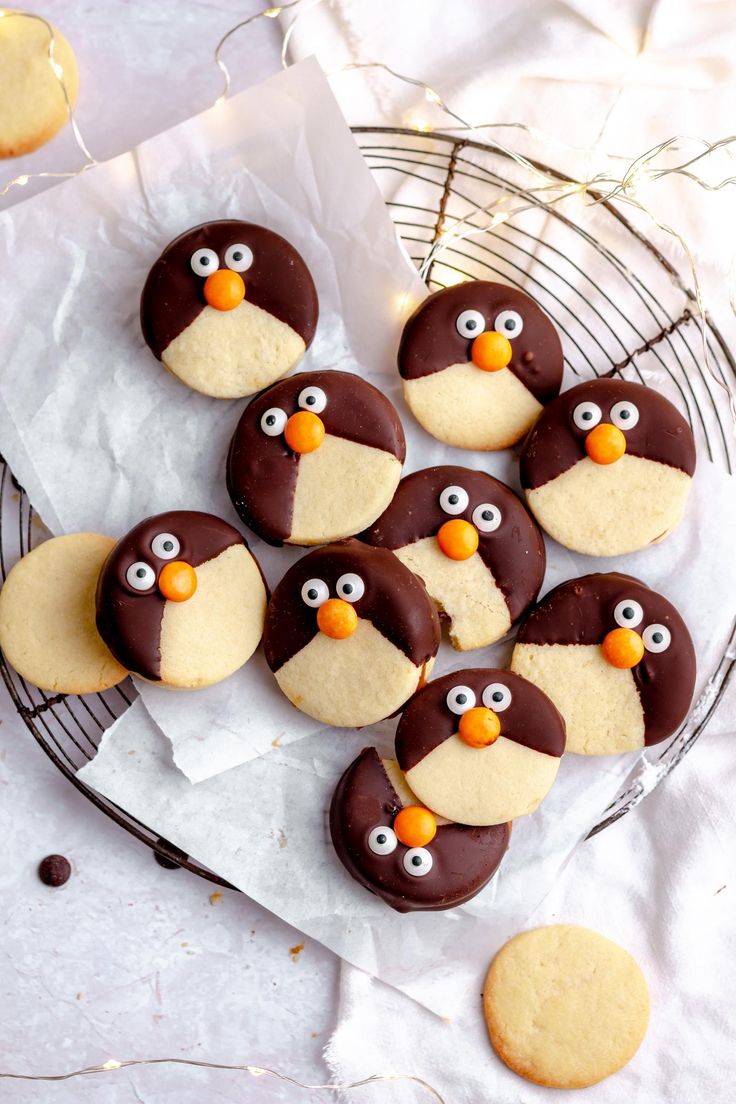 chocolate penguin cookies are arranged on a wire rack