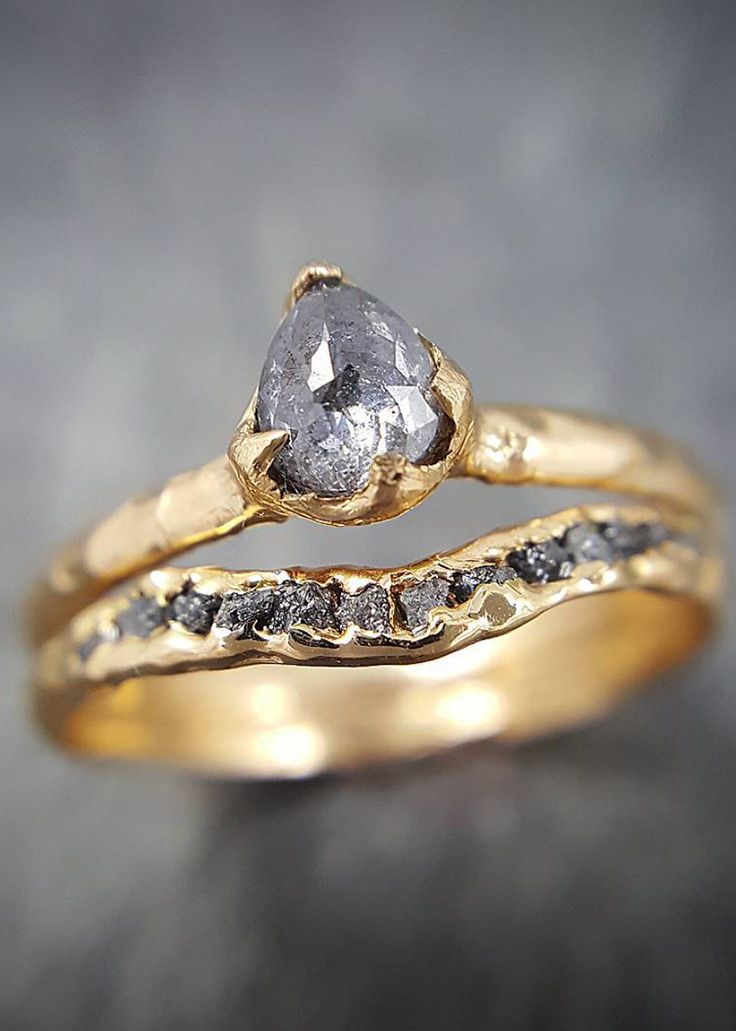 two gold wedding bands with a diamond in the center and an engagement ring on top