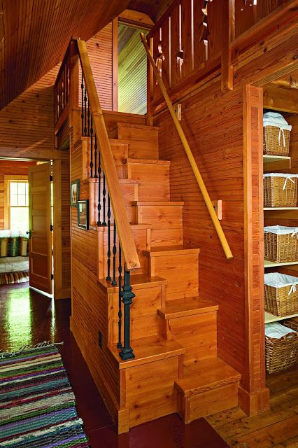 a wooden staircase in a house with baskets on the floor next to it and an area rug