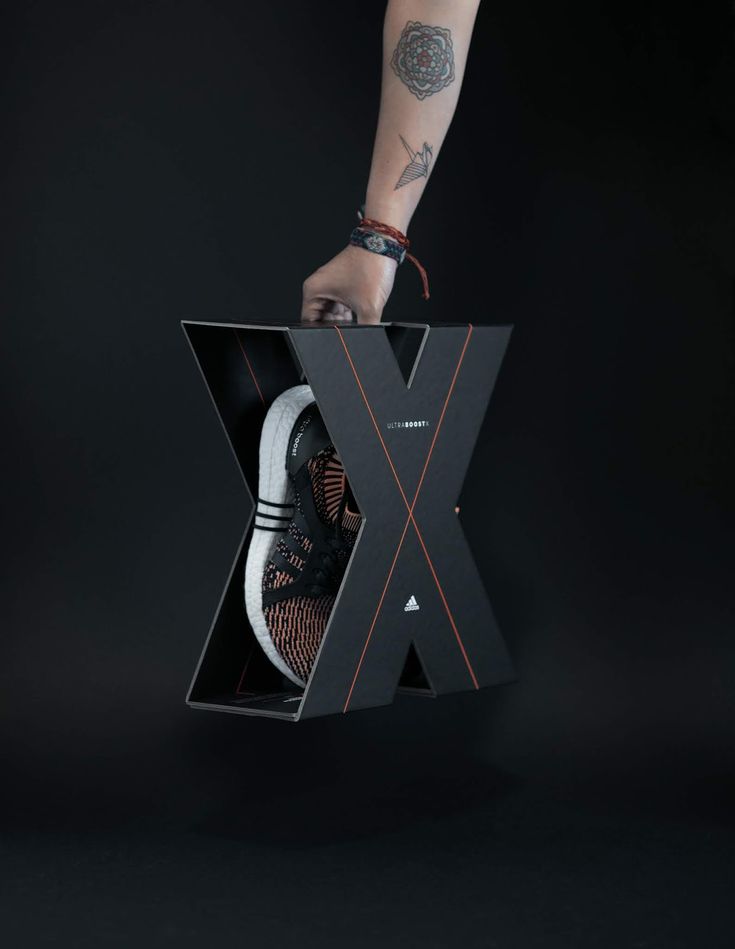 a person holding an x box with their shoes inside on a black background in front of the camera