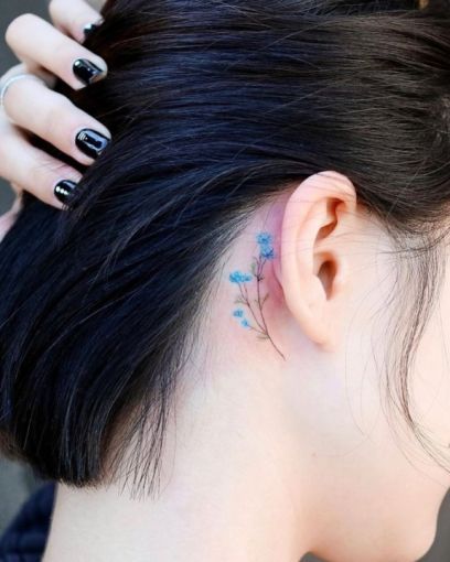 a woman with black nail polish on her left ear and behind her ear is a small blue flower