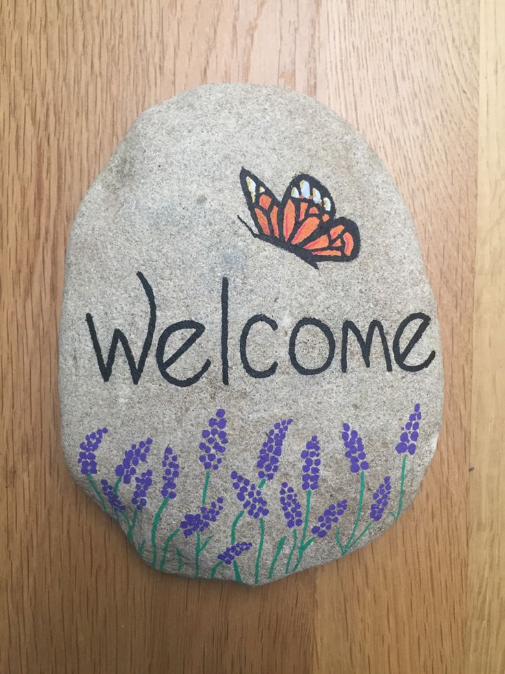 a rock with the word welcome painted on it and a butterfly sitting on top of it