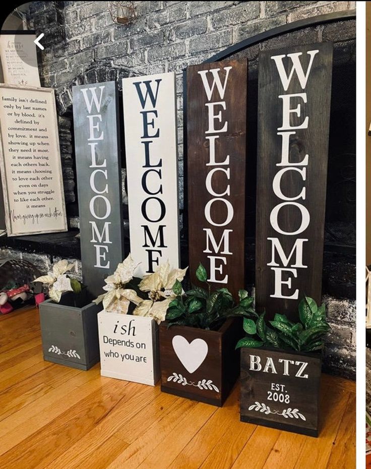 three wooden welcome signs sitting on top of a hard wood floor next to a fireplace