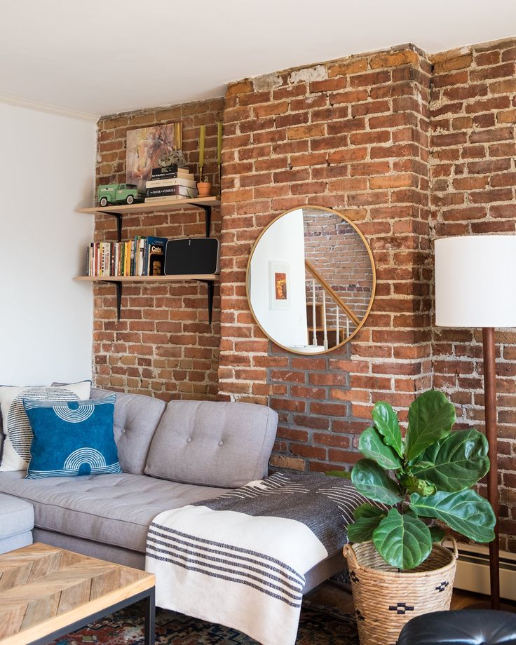 a living room filled with furniture and a large mirror on the brick wall above it