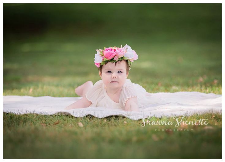 a baby laying on the grass wearing a flower crown