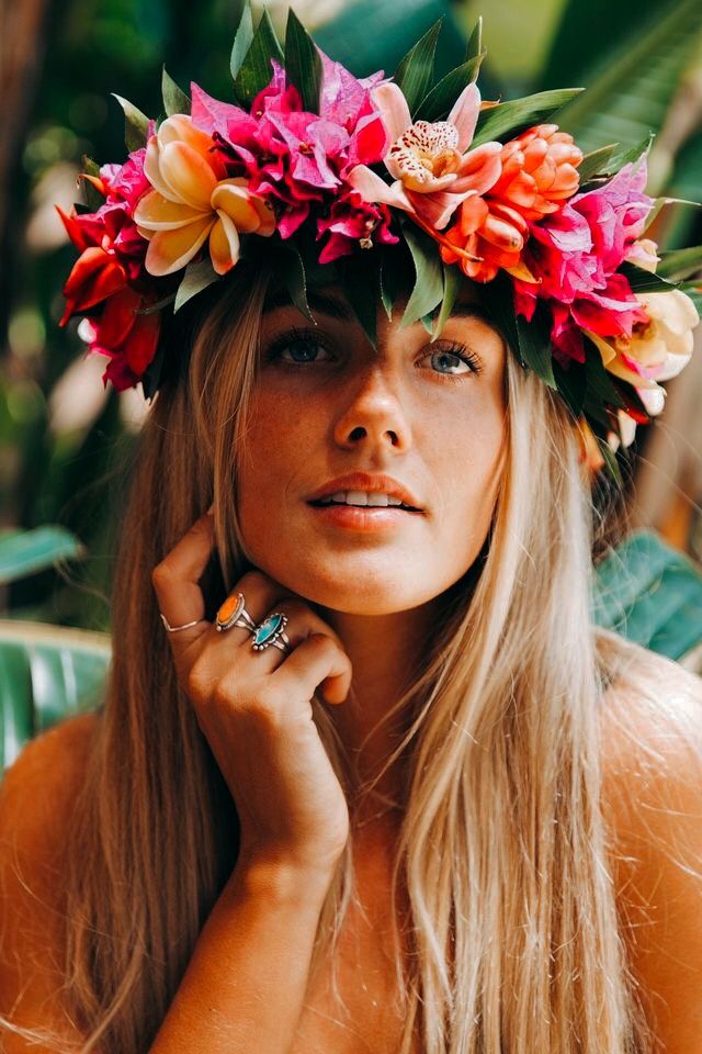 a woman wearing a flower crown with her hands on her face and looking off to the side