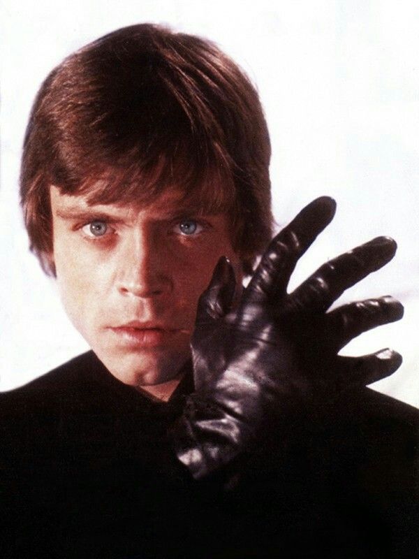 a man in black shirt and leather gloves holding his hand up to the camera with both hands