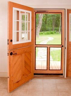 an open wooden door in front of a brick floored entry way to a yard