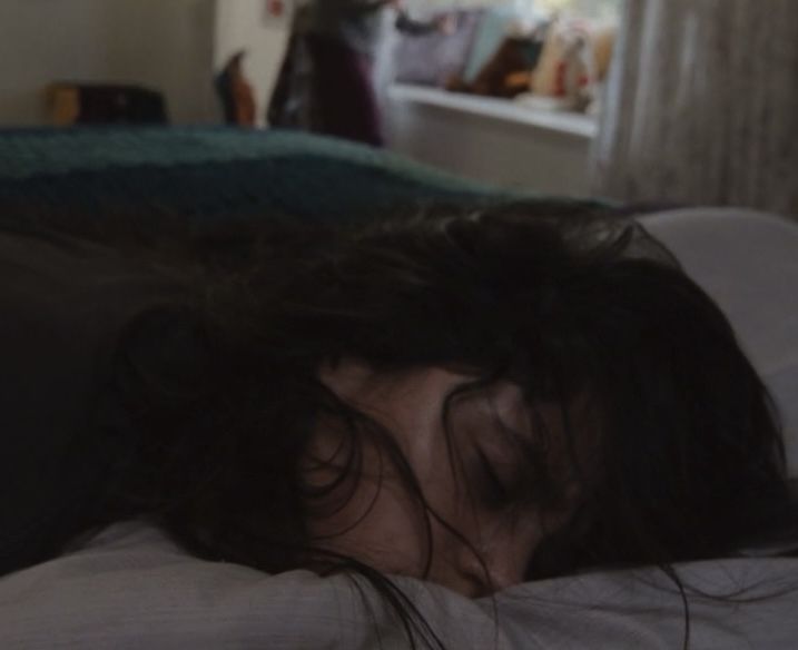 a woman laying in bed with her head on the pillow