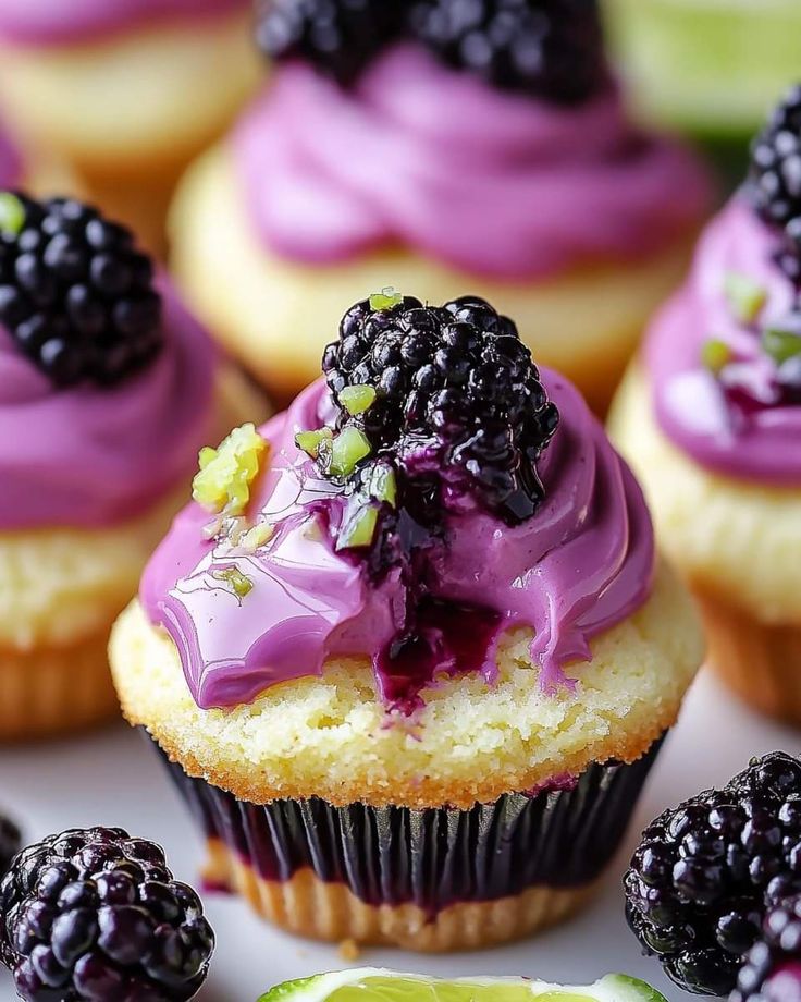 cupcakes with purple frosting and blackberries on top, surrounded by lime slices