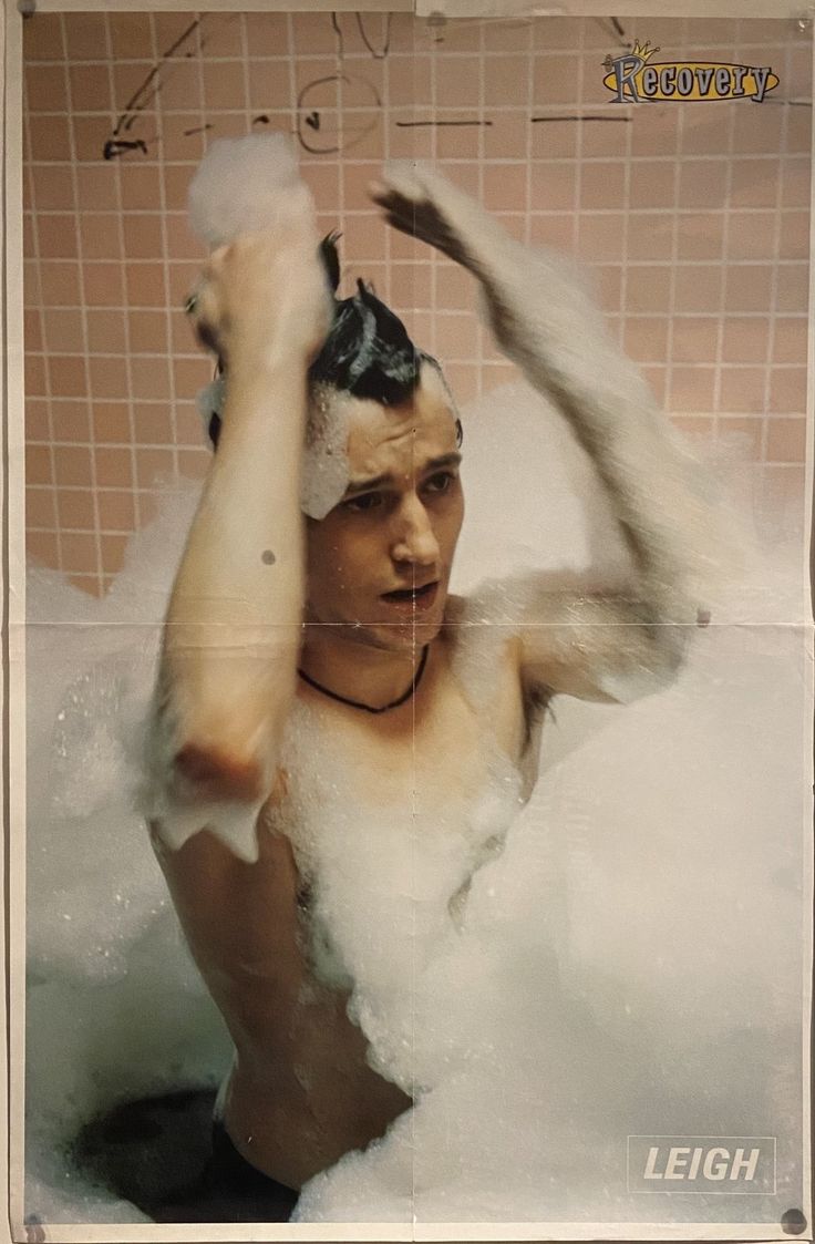 a man is in the bathtub with foam on his head and hands above his head