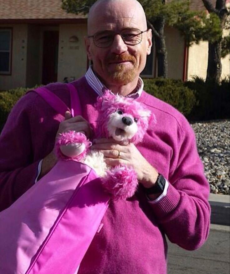 an older man holding a pink teddy bear in front of a house on the street