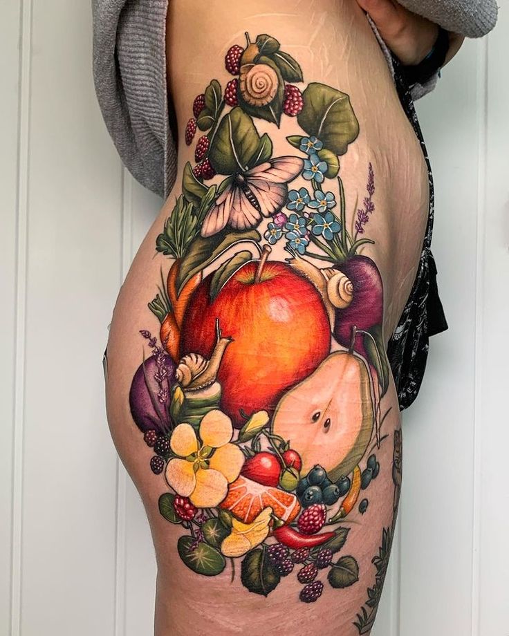 a woman's thigh with fruit and flowers on it