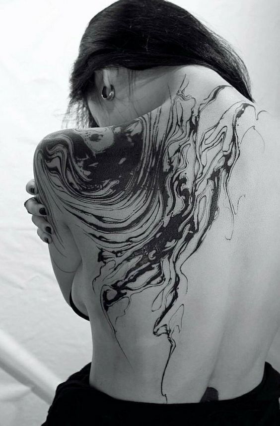 the back of a woman's shoulder with black ink on it and an abstract design