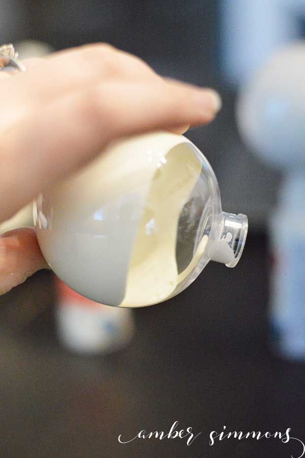 a woman is pouring something into a small glass cup with the lid down and her hand holding it