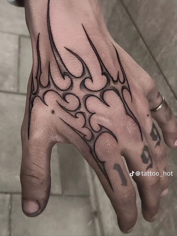 a man's hand with an intricate tattoo design on his left thumb and fingers