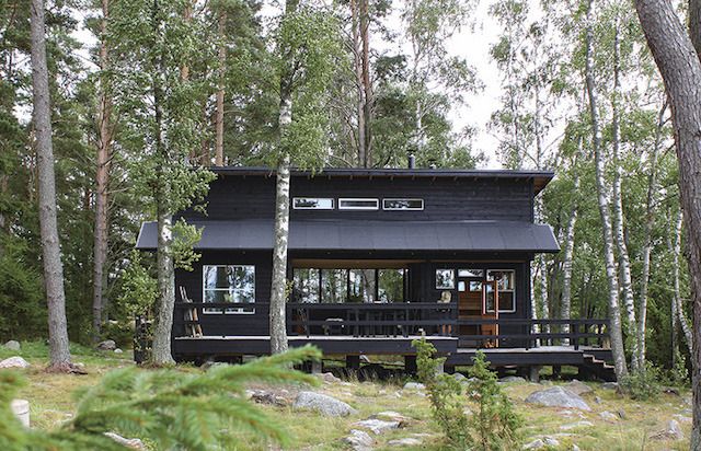 a black cabin in the woods surrounded by trees