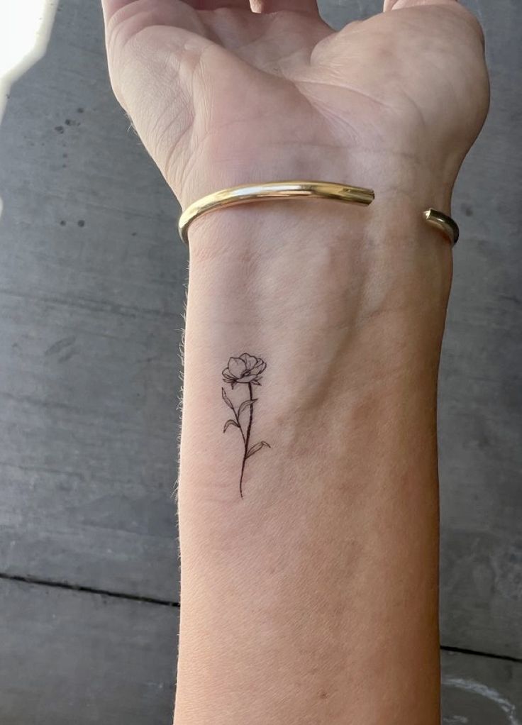 a woman's arm with a small flower tattoo on the left side of her wrist