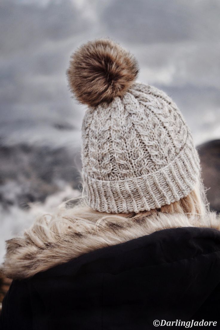 a woman wearing a white hat with a brown pom - pom on it