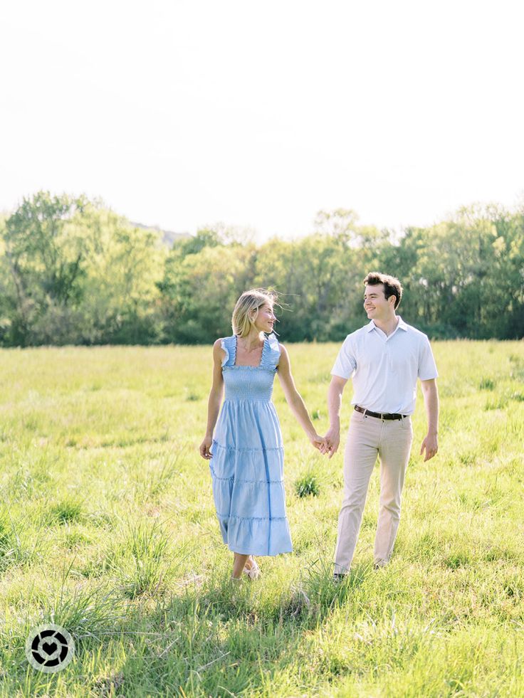 a man and woman holding hands walking through the grass