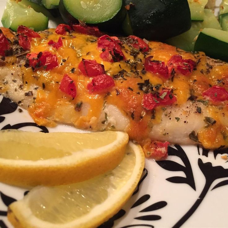 a piece of fish on a plate with lemons and cucumbers