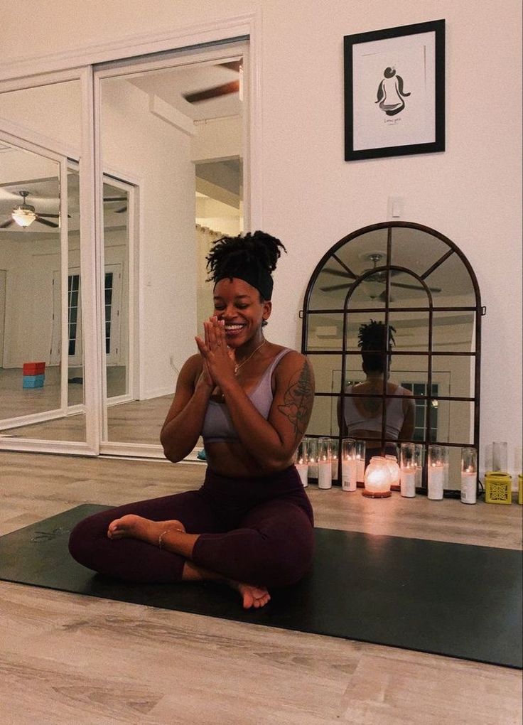 a woman sitting on a yoga mat with her hands together