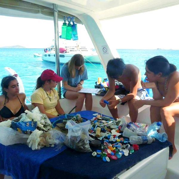 several people sitting on a boat in the ocean eating food and concoctions