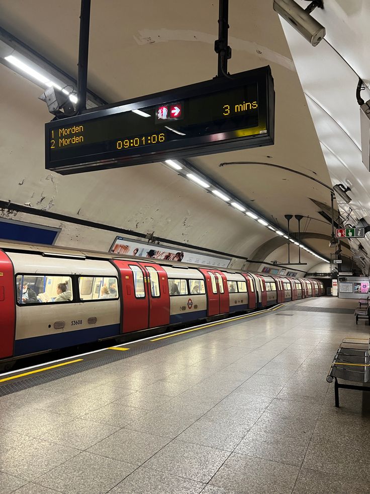 an empty subway station with people waiting for the train to stop at it's platform