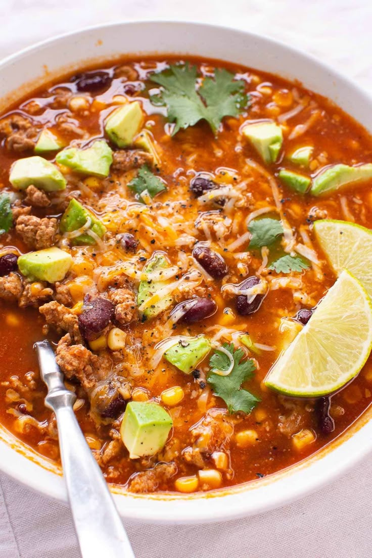 a white bowl filled with chili, beans and avocado garnished with cilantro