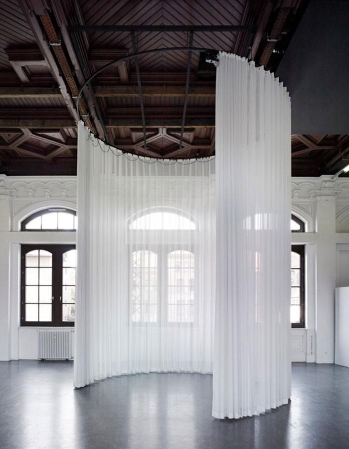 an empty room with white curtains hanging from the ceiling