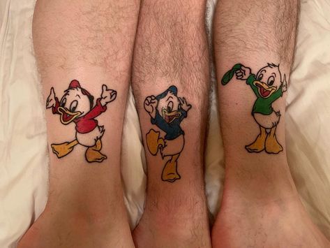 two people with matching tattoos on their legs, both wearing ducky and donald mouse outfits