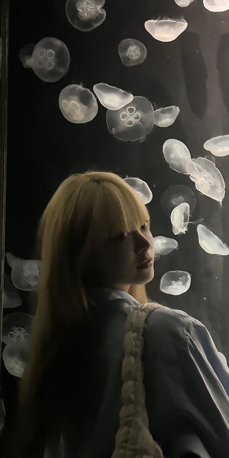 a woman is standing in front of jellyfish