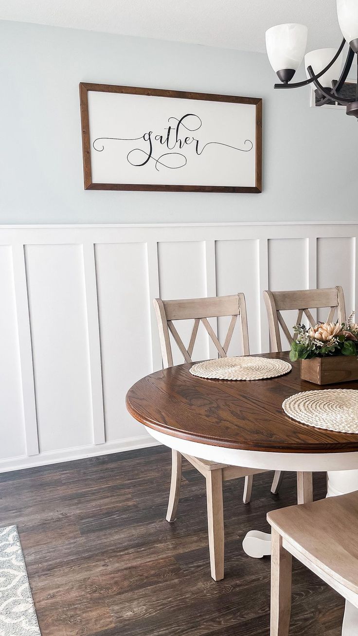 a dining room table with two chairs and a wooden sign above it that says gather