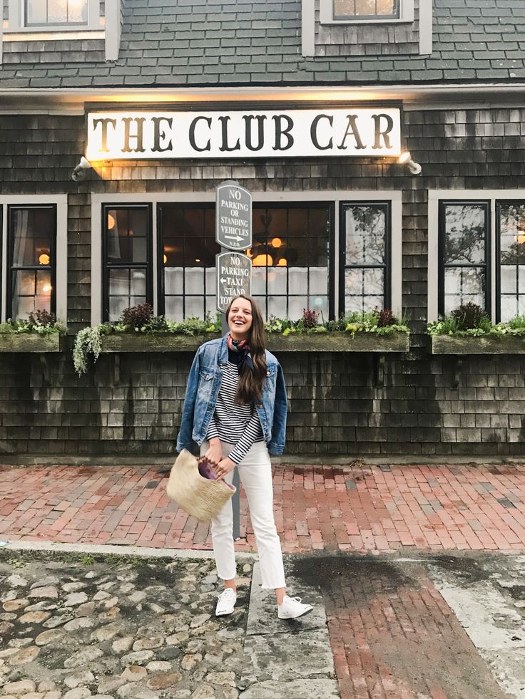 a woman is standing in front of the club car building with her hat on and smiling