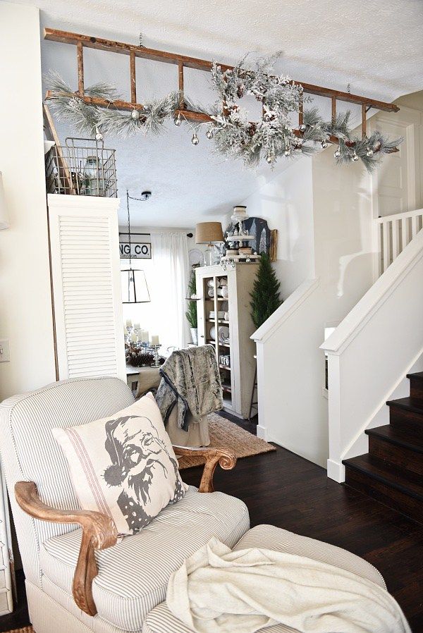 a living room filled with furniture next to a stair case covered in christmas garlands