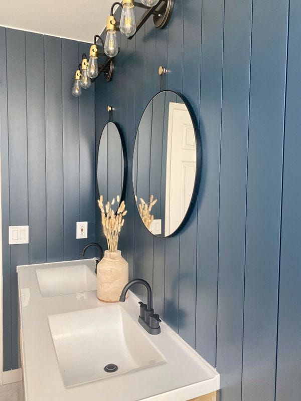 a white sink sitting under a bathroom mirror next to a wall mounted faucet