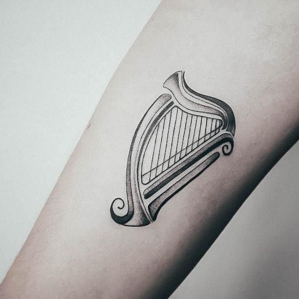 a tattoo with a harp on the arm