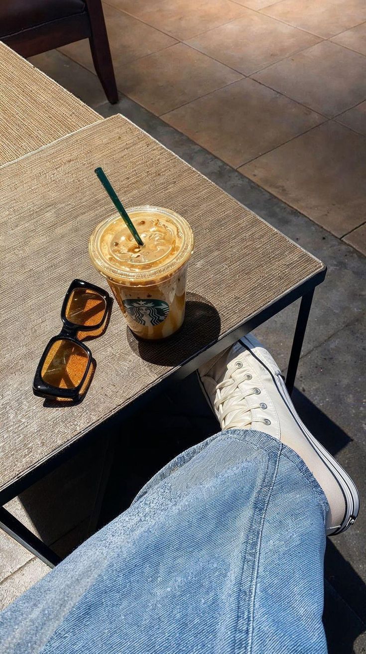 a person sitting at a table with their feet on the coffee table and sunglasses next to them