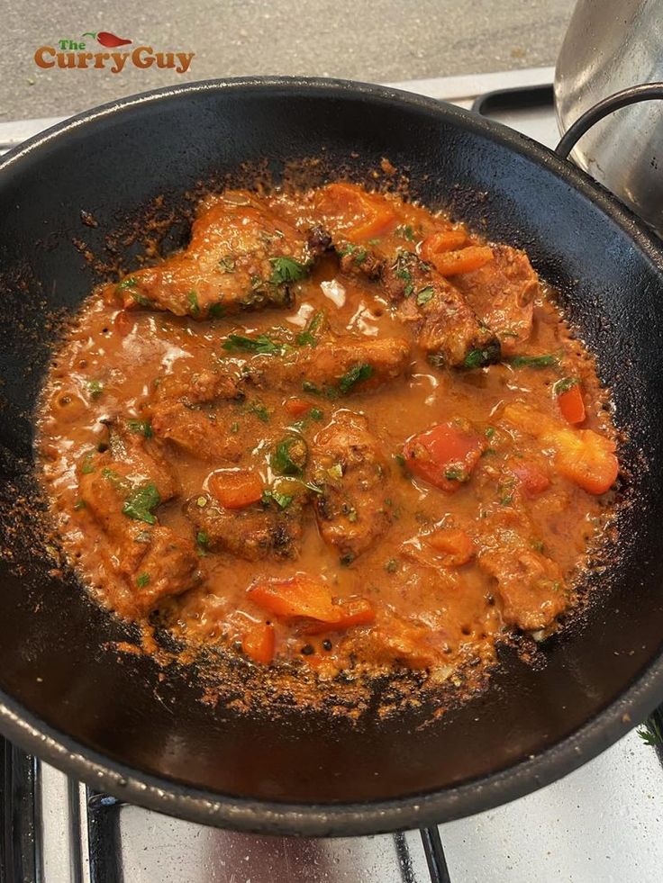 a skillet filled with meat and vegetables cooking on the stove