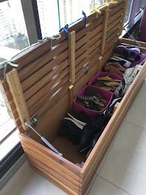 a wooden bench filled with lots of purses next to a large window on top of a white tiled floor