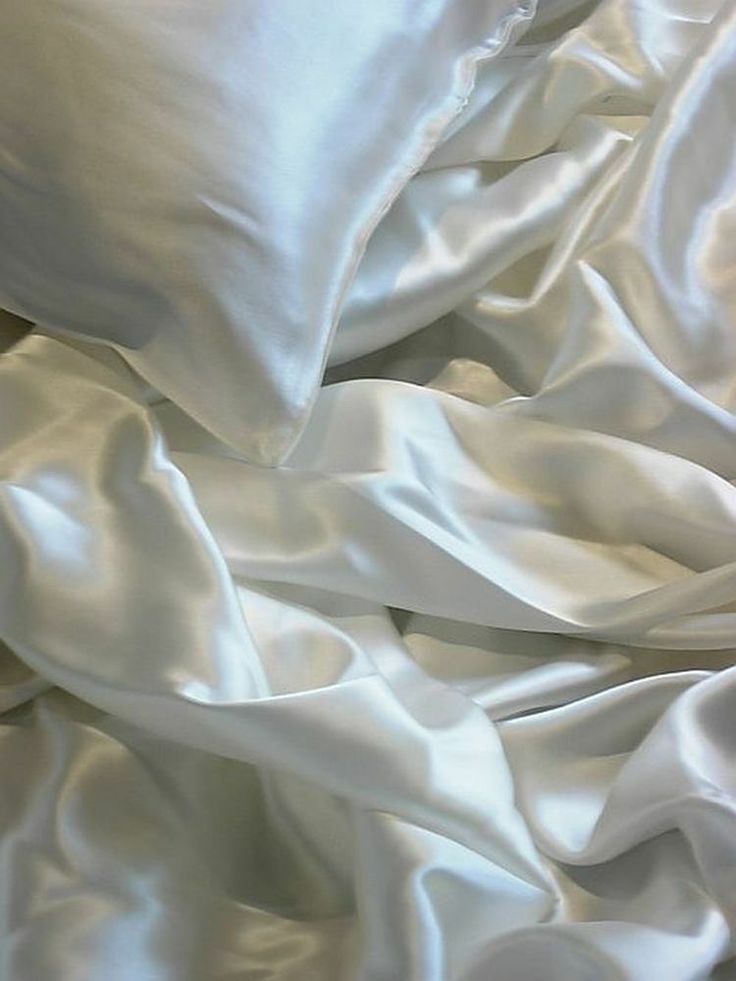 white sheets and pillows are piled together on top of each other in the bedding