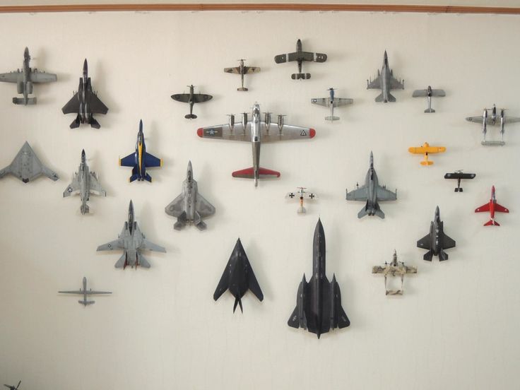 a bunch of fighter jets are hanging on the wall in front of a white wall