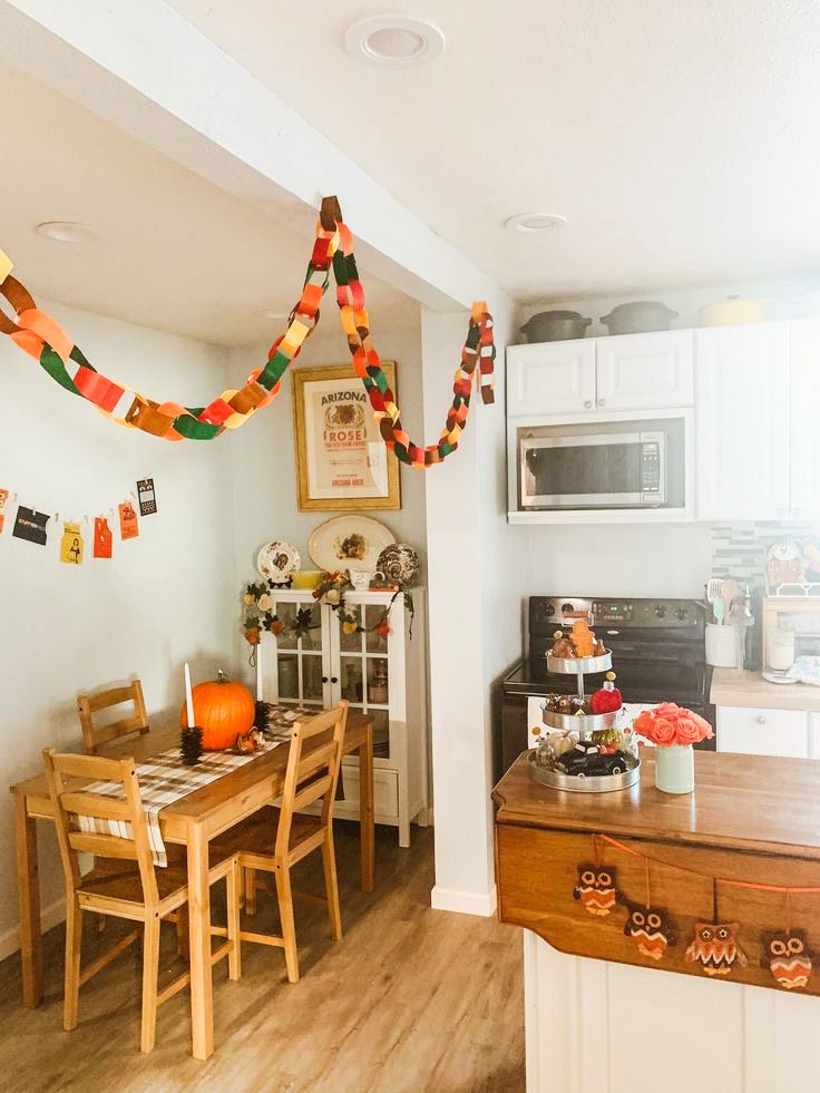 the kitchen is decorated for halloween with garlands hanging from the ceiling and pumpkins on the table