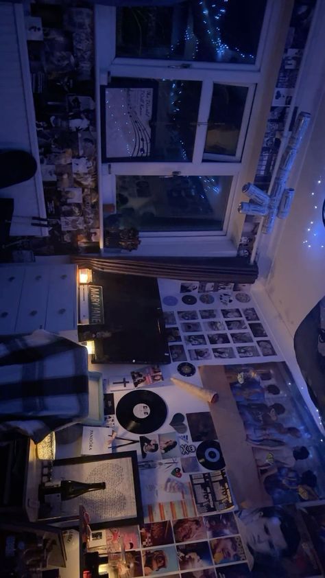 a living room filled with furniture and pictures on the floor next to a window at night