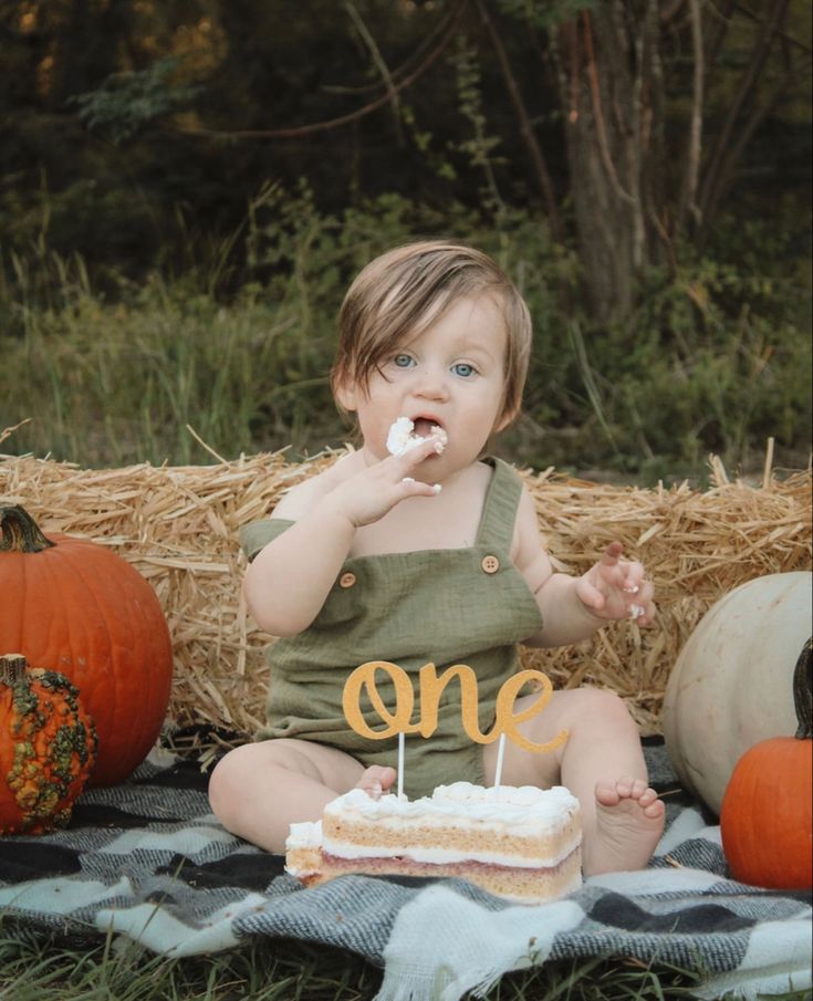 a baby sitting on a blanket eating cake