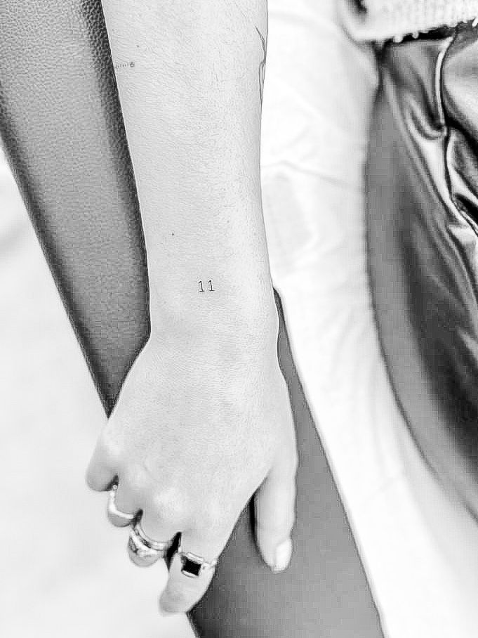 a person with a small tattoo on their left arm holding onto a purse and the other hand