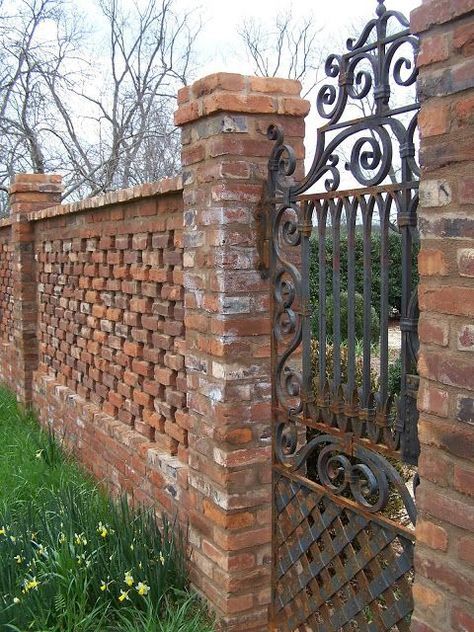 a brick fence with wrought iron gate