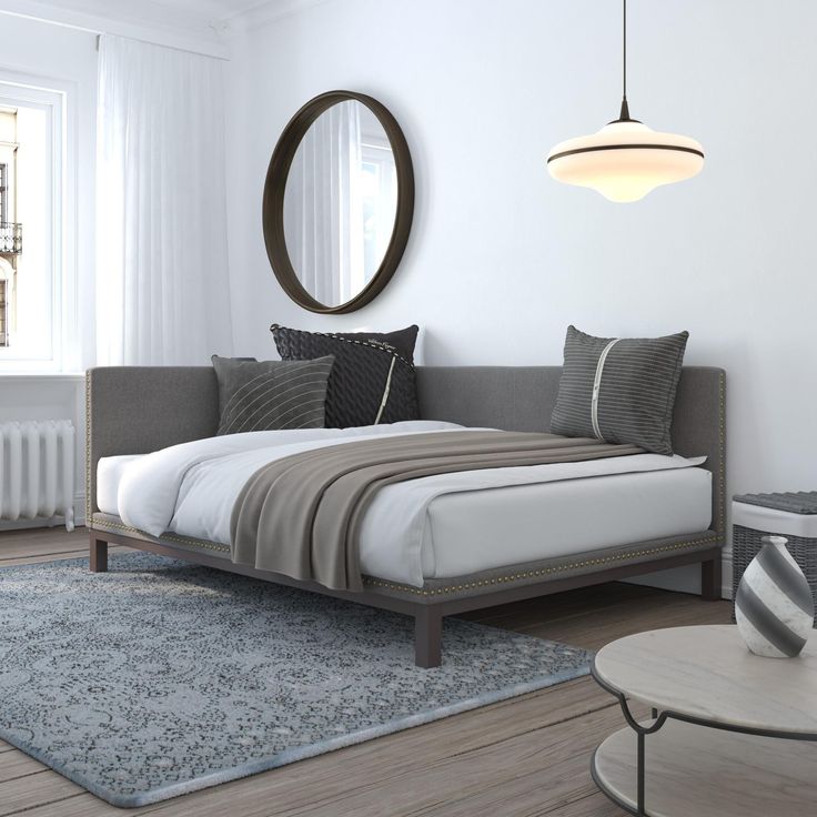 a bed sitting on top of a wooden floor next to a white couch and table